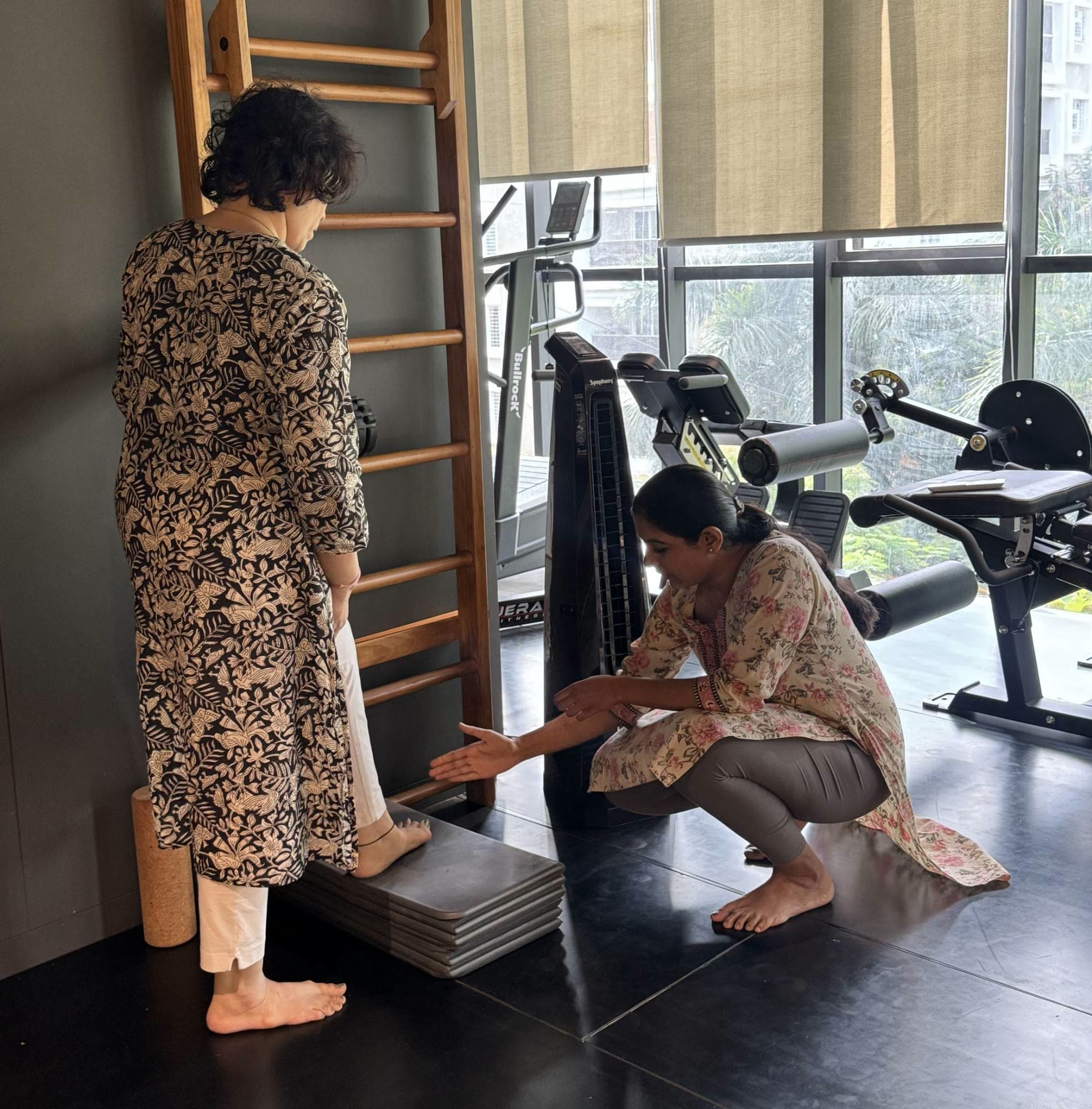 Physiotherapist Shushti Belekar assessing a client's ankle mobility at the wall bars